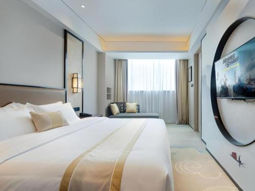 a hotel room with a large bed and a flat screen tv at Yuan Culture Hotel Shenzhen World Shajing in Shenzhen