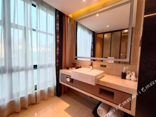 a bathroom with a sink and a large mirror at Yuan Culture Hotel Shenzhen World Shajing in Shenzhen