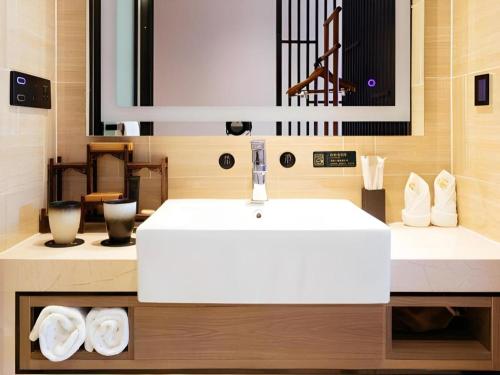 a bathroom with a white sink and a mirror at Yuan Culture Hotel Shenzhen World Shajing in Shenzhen