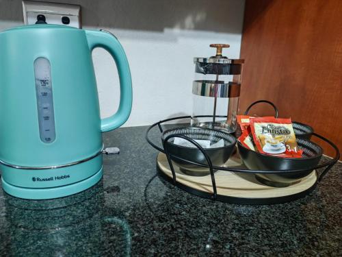 a blue kettle sitting on a counter next to a bowl at Pelican Palms Aston Jeffreys Bay in Jeffreys Bay