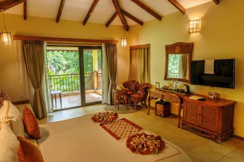 a living room with a bed a desk and a television at The Fern Gir Forest Resort, Sasan Gir - A Fern Crown Collection Resort in Sasan Gir