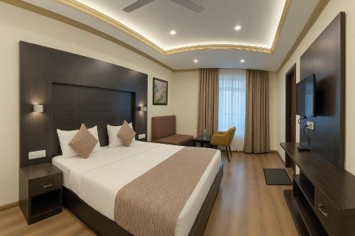 a hotel room with a bed and a flat screen tv at Crown Plaza Residency in Srinagar