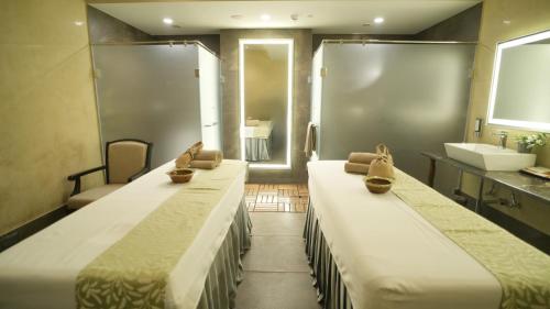 two beds in a room with a sink and a bathroom at Gift City Club, a member of Radisson Individuals in Gandhinagar