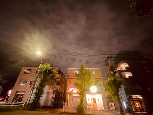a couple of buildings on a street at night at CCCOFFEE HOSTEL Kobe in Kobe