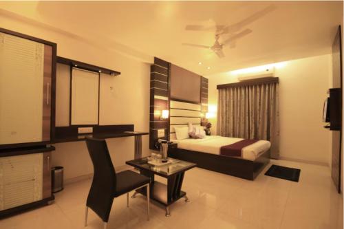 a bedroom with a bed and a table and a chair at Hotel Apple Inn Vapi in Vapi