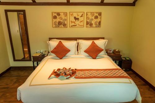 a bedroom with a large bed with orange pillows at The Fern Gir Forest Resort, Sasan Gir - A Fern Crown Collection Resort in Sasan Gir
