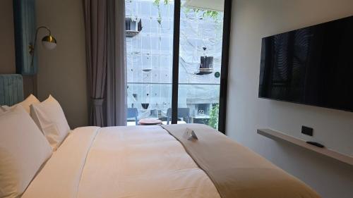 a bedroom with a large white bed with a window at La Green Hotel and Residence in Bang Tao Beach