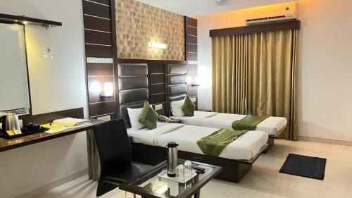 a hotel room with two beds and a table at Hotel Apple Inn Vapi in Vapi
