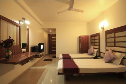 a bedroom with two beds and a flat screen tv at Hotel Apple Inn Vapi in Vapi