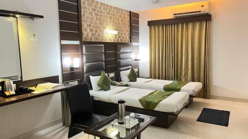 a hotel room with two beds and a table at Hotel Apple Inn Vapi in Vapi
