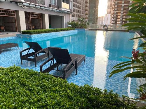 a swimming pool with two chairs and a table at Central Phnom Penh Sky Suite in Phnom Penh