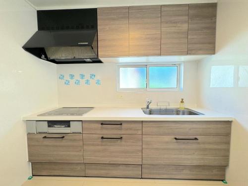 a kitchen with wooden cabinets and a sink at Grande Ortho Okinawa Villa Onna 3 - Vacation STAY 83213 in Onna