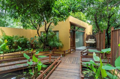 a wooden walkway leading to a house with trees at The Fern Gir Forest Resort, Sasan Gir - A Fern Crown Collection Resort in Sasan Gir