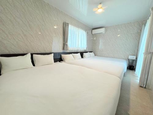 two beds in a room with white sheets at Grande Ortho Okinawa Villa Onna 3 - Vacation STAY 91370 in Onna