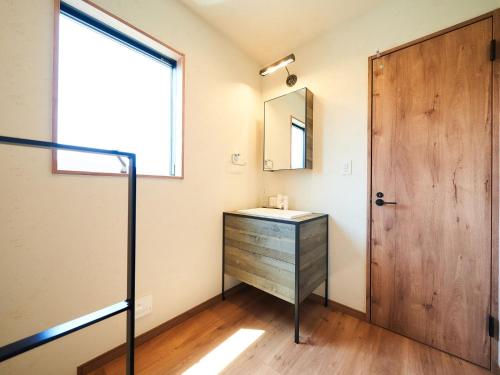 a bathroom with a sink and a wooden door at Rakuten STAY HOUSE Kujukuri Ichinomiya 102 3LDK with BBQ terrace in Ichinomiya
