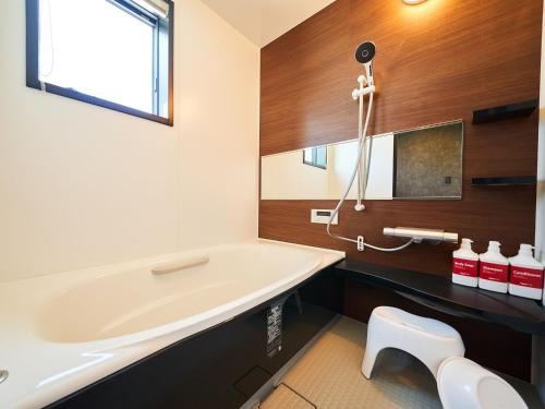 a bathroom with a tub and a sink at Rakuten STAY HOUSE Kujukuri Ichinomiya 102 3LDK with BBQ terrace in Ichinomiya