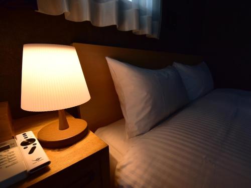 a lamp on a night stand next to a bed at Rakuten STAY HOUSE Kujukuri Ichinomiya 102 3LDK with BBQ terrace in Ichinomiya