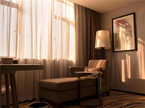 a hotel room with a chair and a lamp at Clear Lake Hotel in Shanwei