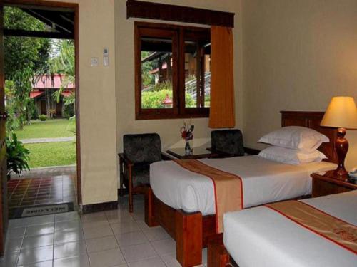 ein Hotelzimmer mit zwei Betten und einem Fenster in der Unterkunft Kalibaru Cottages in Banyuwangi
