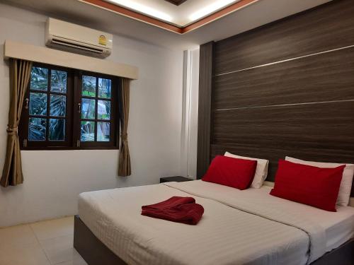 a bedroom with a bed with red pillows and a window at Tok Little Hut in Rayong