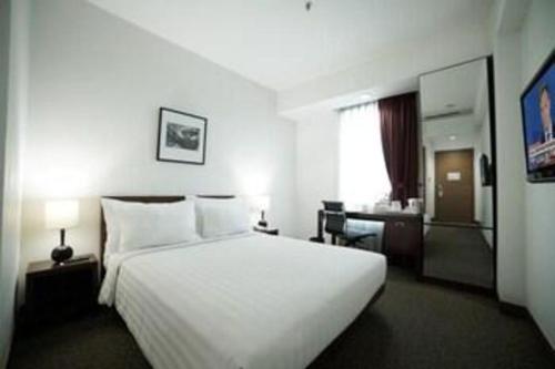 a hotel room with a large white bed and a desk at PARK HOTEL Cawang Jakarta in Jakarta