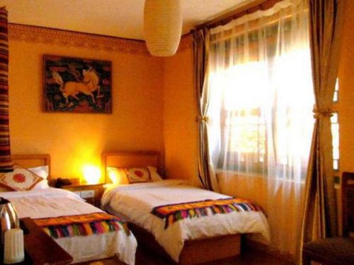 a bedroom with two beds and a window at Tashitakge Hotel in Lhasa