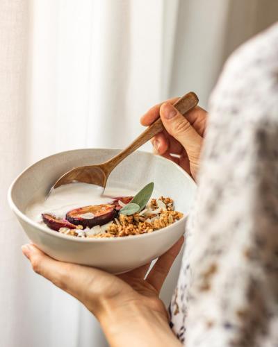 a person holding a bowl of cereal with a spoon at Bayflowers Guest House in Cape Town
