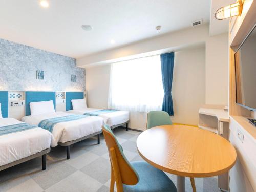 a hotel room with two beds and a table at Comfort Hotel Ishigaki Island in Ishigaki Island
