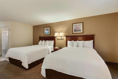 a hotel room with two beds with white sheets at MainStay Suites Fitchburg - Madison in Madison