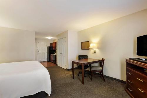 a hotel room with a bed and a desk and a television at MainStay Suites Fitchburg - Madison in Madison