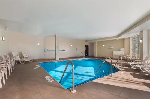 a swimming pool in a room with chairs at MainStay Suites Fitchburg - Madison in Madison