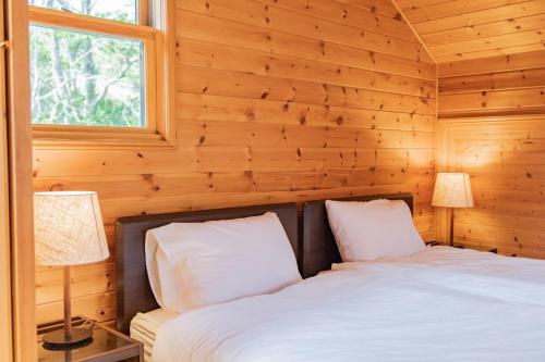 a bedroom with wooden walls and a bed with two lamps at Relaxing Log Cabin IZU HOUSE- Vacation STAY 85769 in Ito