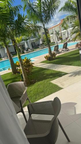 a patio with chairs and a swimming pool with palm trees at WRparaiso in Boca Chica