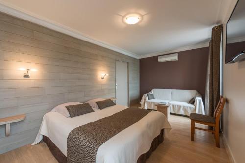 a hotel room with a bed and a chair at Logis Hotels - Au Poisson d'Argent - Hôtel 3 étoiles et restaurant in Le Mesnil-en-Vallée