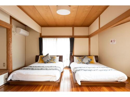 two beds in a room with a window at Hana Azusa - Vacation STAY 86863 in Yufuin