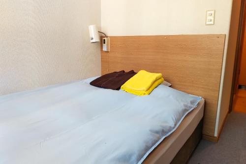 a bed in a room with a yellow towel on it at Hotel Frontier in Ishinomaki