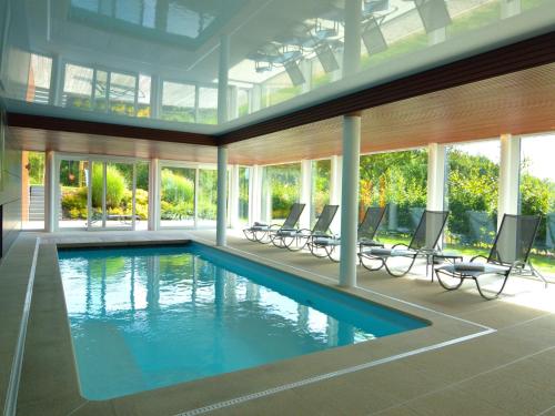 una piscina in una casa con sedie e finestre di Malmedy Hillside Spa Retreat a Malmedy