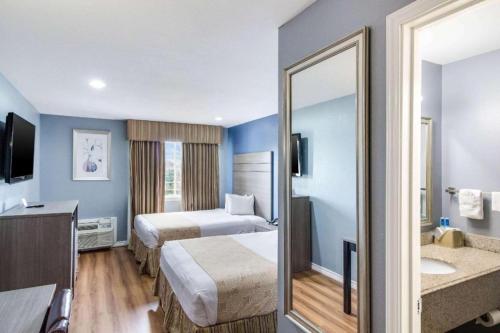 a hotel room with two beds and a mirror at Rodeway Inn & Suites Port Arthur - Groves in Port Arthur