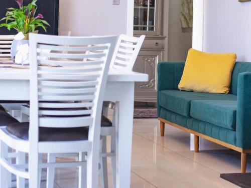 a dining room with a white table and a green chair at Julinas Self Catering Apartments in Parow