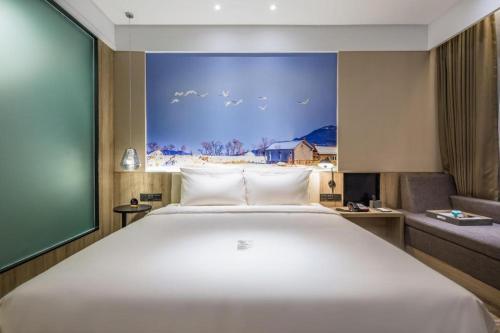 a bedroom with a large white bed and a couch at Atour Hotel Weihai Shidao in Dongshan