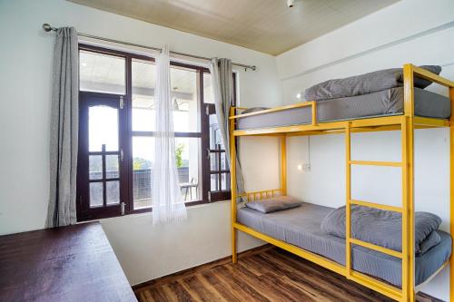 a bunk bed room with two bunk beds and a window at Young Monk Hostel & Cafe Dharamkot in McLeod Ganj
