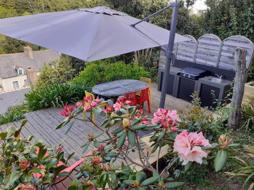 a patio with an umbrella and a chair and flowers at Maison de charme cancalaise in Cancale