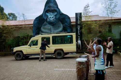a group of people standing in front of a van with a monkey at Mountain Gorilla View Lodge in Ruhengeri