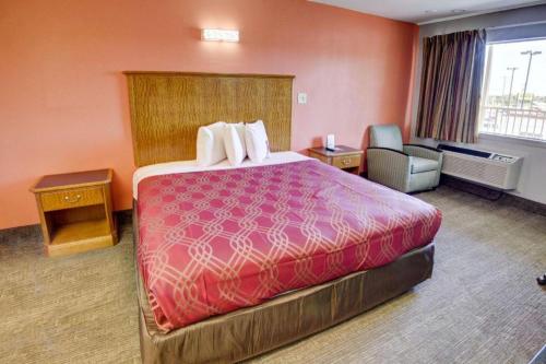 a hotel room with a large bed and a chair at Econo Lodge Airport in Norfolk