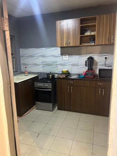 a kitchen with wooden cabinets and a stove at Sarah homes in Isheri-Olofin