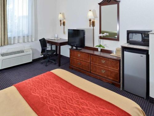 a hotel room with a bed and a desk with a television at Comfort Inn & Suites in Riverton