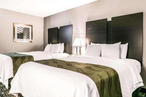 two beds in a hotel room with white sheets at Suburban Studios Mason Hwy 42 in Mason
