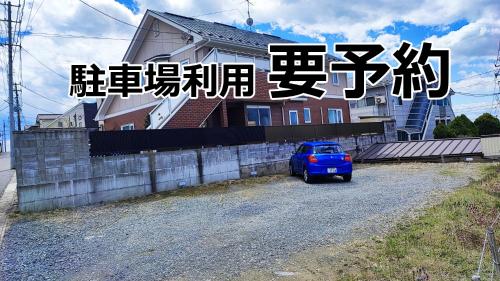 a blue car parked in front of a house at Hotel Frontier in Ishinomaki