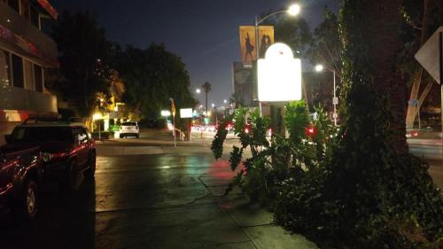 a city street at night with a sign on the sidewalk at Highland Gardens Hotel in Los Angeles