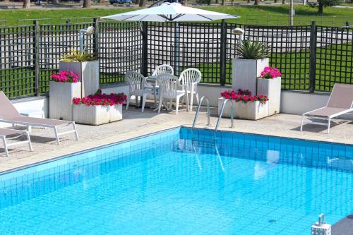 a swimming pool with chairs and a table and an umbrella at Park Hotel in Castrocaro Terme